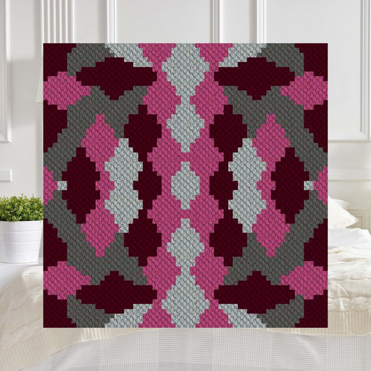 Overlapping diamond shapes in coral, gray, and burgundy yarn blocks forming a rich geometric pattern