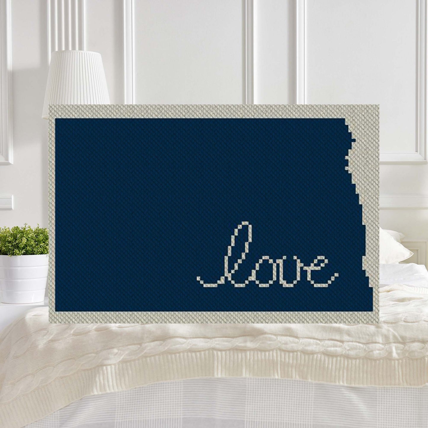 Pixel-art North Dakota outline with heart motif in two contrasting yarn blocks