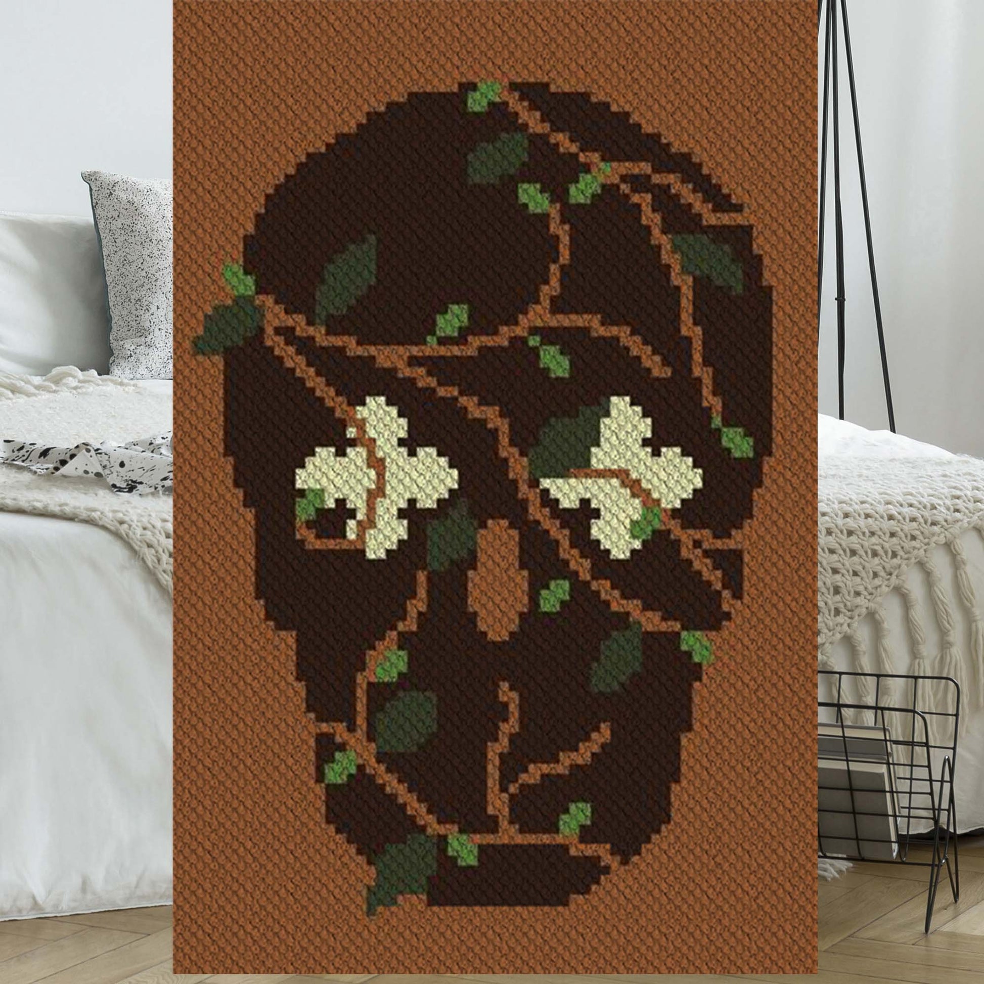 Skull silhouette entwined with flowering vines in earthy yarn colors