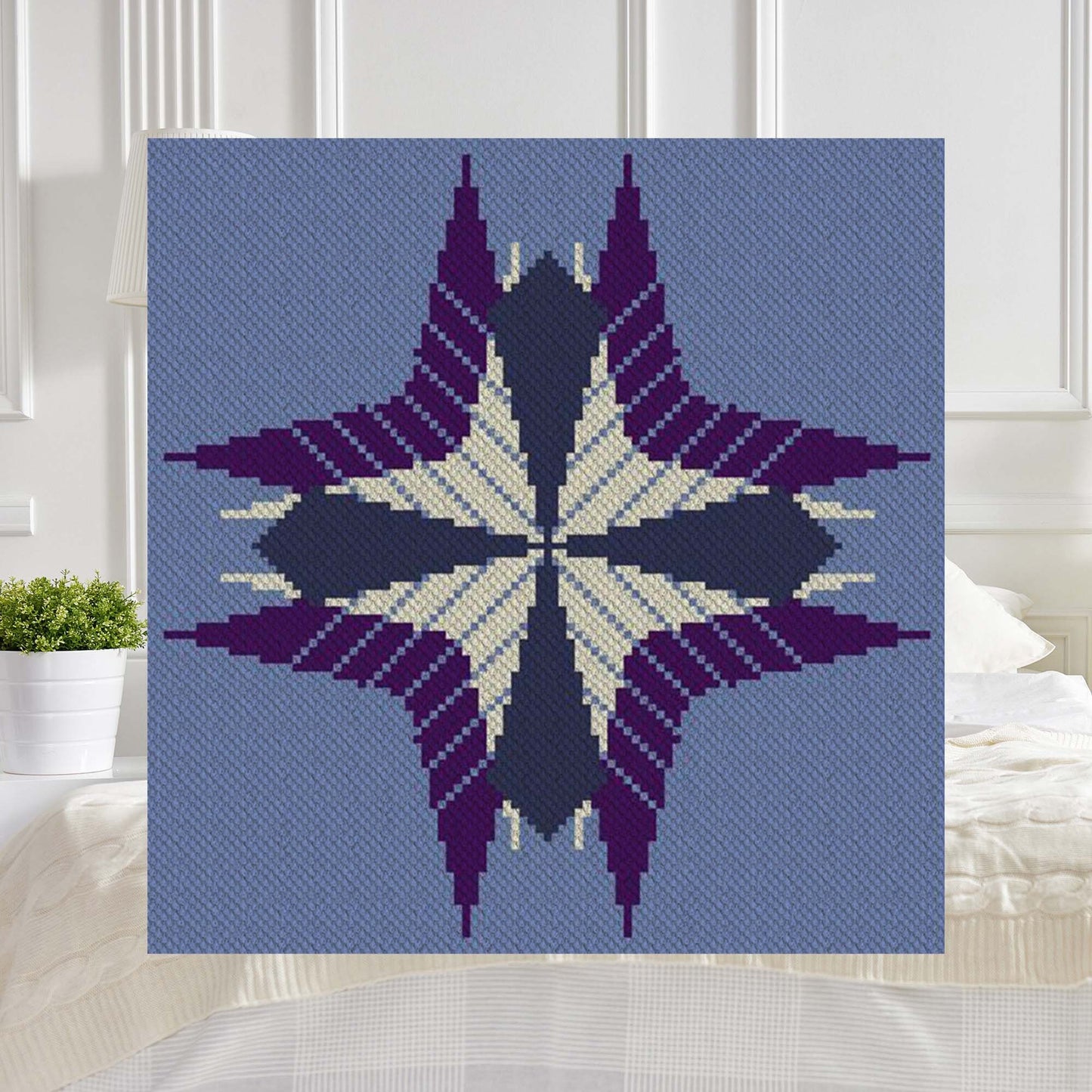 Geometric starburst afghan in shades of purple and blue, rendered in corner-to-corner pixel blocks