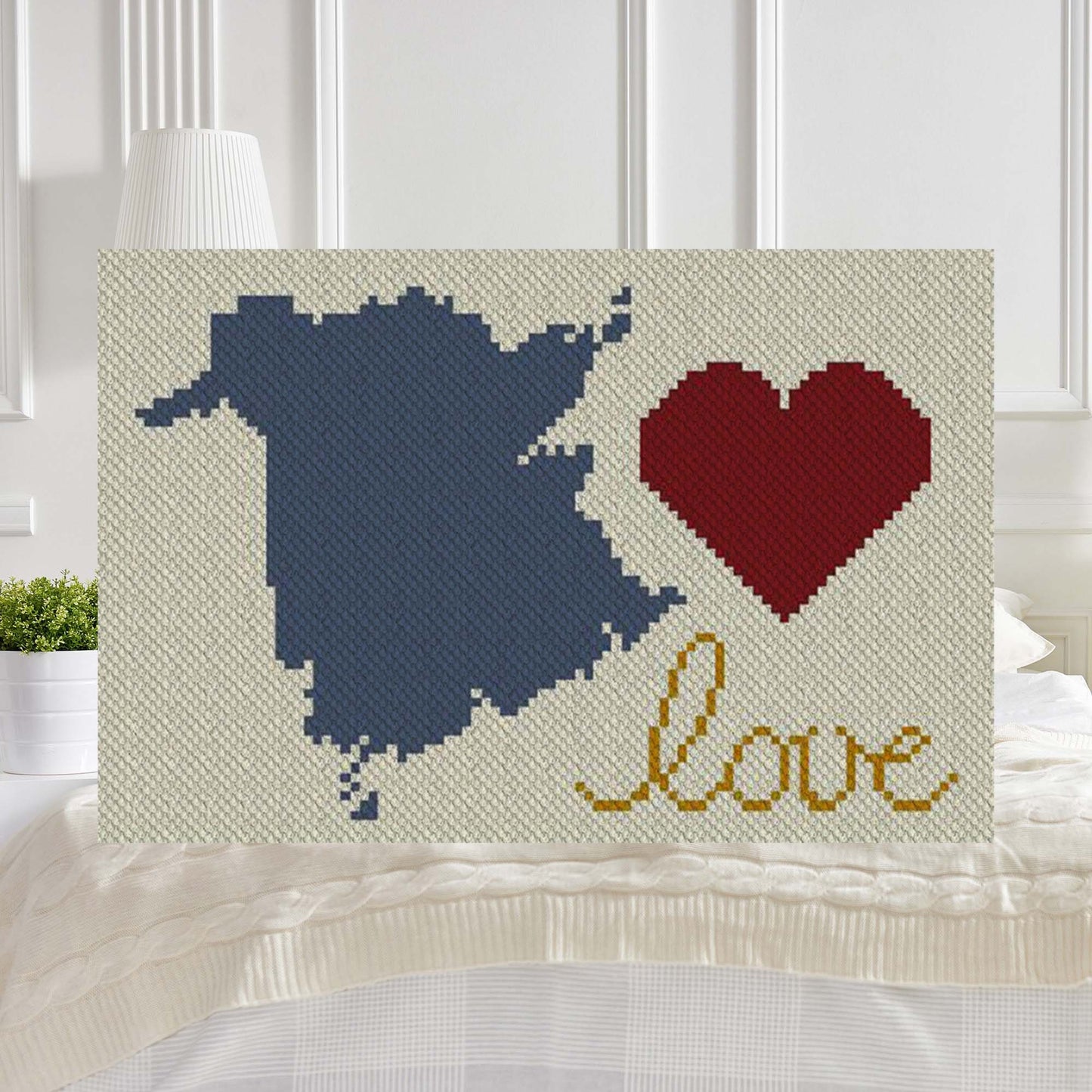 Pixel-art New Brunswick outline with heart motif in three yarn colors