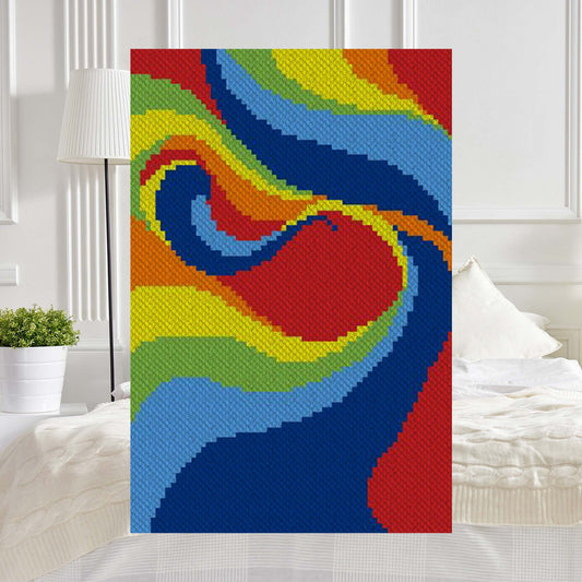 Swirling diagonal bands of red, orange, yellow, green, light blue, and deep blue forming a rainbow swoosh in C2C blocks